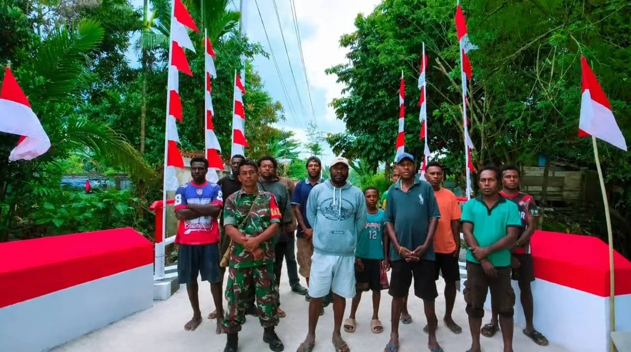 Markus Awaiti bersama warga Kampung Kamoro Jaya saat berada diatas jembatan yang rampung dibangun.