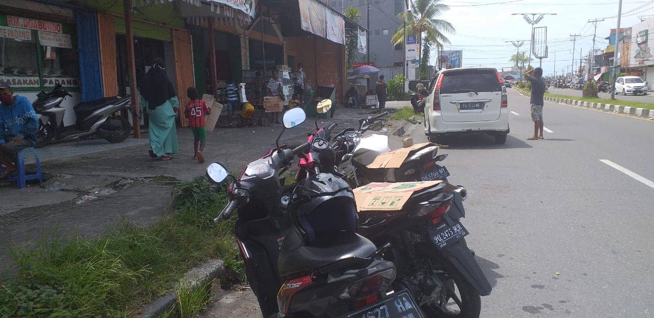 Para bocah jasa penutup motor menggunakan karton di jalan Yos Sudarso Timika