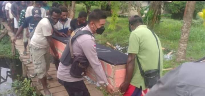 Personil Polsek Onggaya terlihat membantu keluarga mengangkat peti jenazah korban penganiayaan.