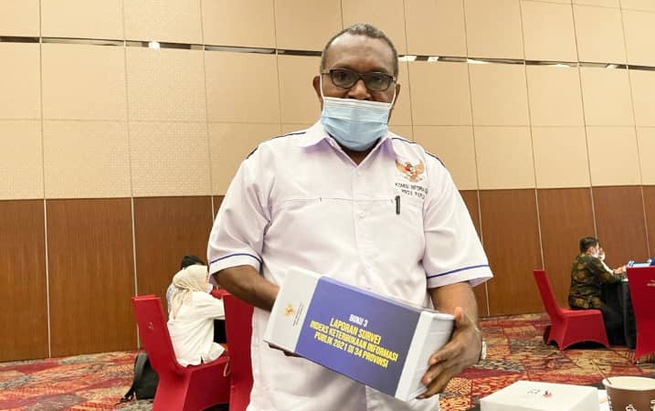 Ketua Komisi Informasi Provinsi Papua Wilhelmus Pigai memegang buku hasil IKIP 2021