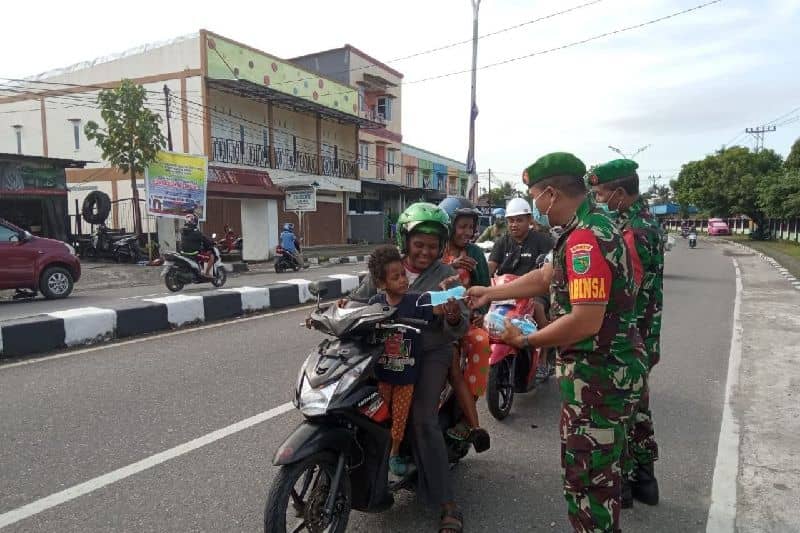 Personel TNI Koramil Mimika Pelda Mustajib memberikan edukasi prokes pengguna jalan dan membagikan masker.
