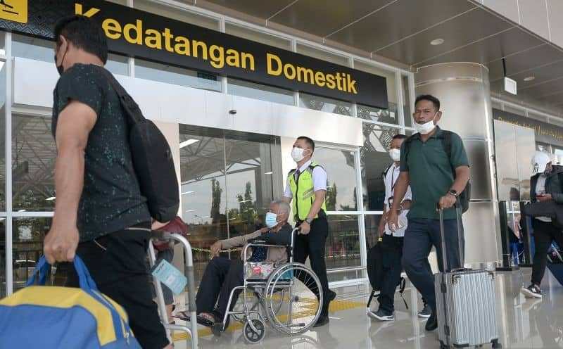 Petugas membantu salah satu penumpang yang tiba di Bandara Internasional Sam Ratulangi, Manado, Sulawesi Utara, Senin (11/4/2022).